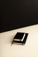 Stack of sleek notebooks with minimalist covers displayed on a wooden desk.