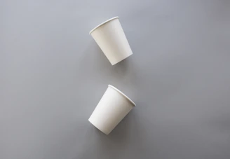 two white disposable cups on gray surface