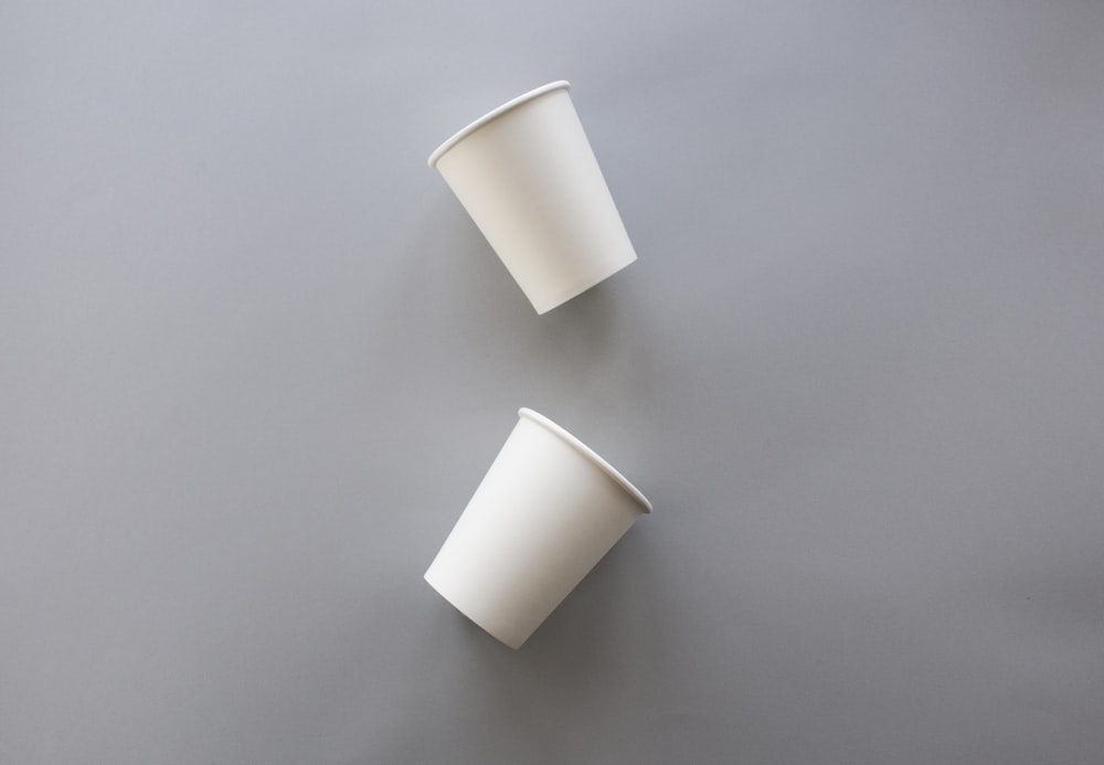 Dos vasos desechables blancos sobre superficie gris