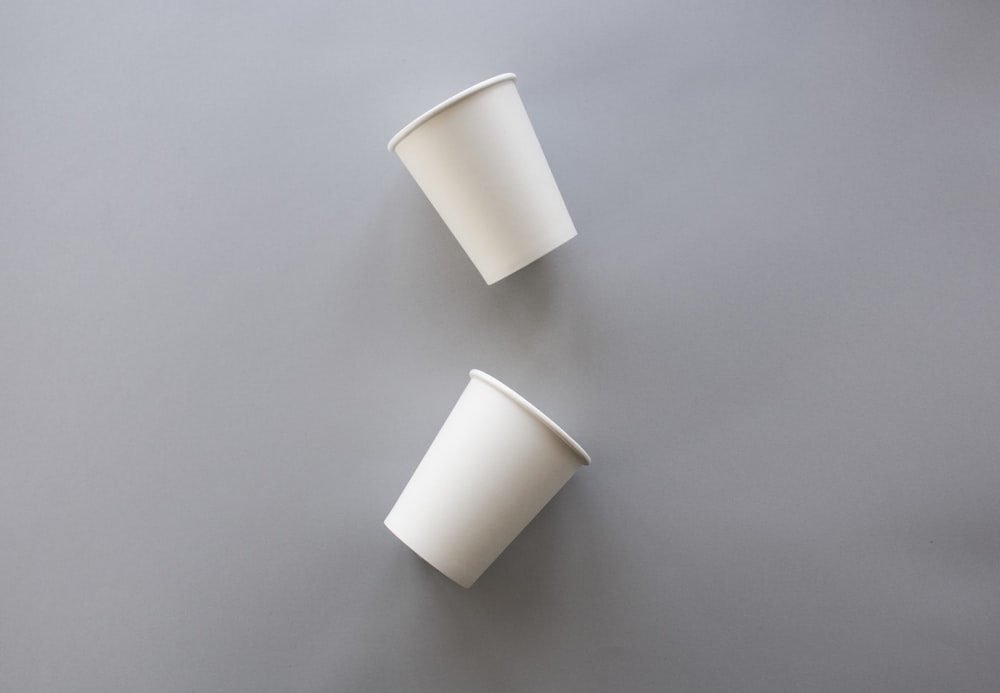 회색 표면에 흰색 일회용 컵 2개