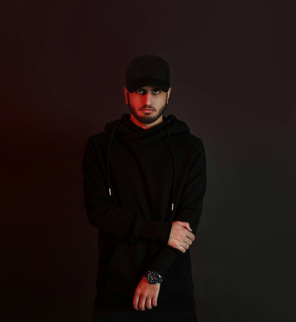 man in black hoodie standing beside wall