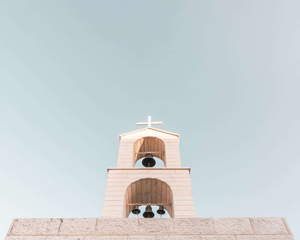 bell on top of concrete building with cross