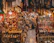 A bustling market scene filled with a variety of intricate metal crafts, jewelry, and textiles. Warm lighting from hanging bulbs illuminates the vibrant colors and detailed patterns of the fabrics draped around the shop. Shelves are crowded with ornate lamps, small sculptures, and an array of traditional ornaments. The narrow aisle adds to the feeling of abundance and richness in the display.