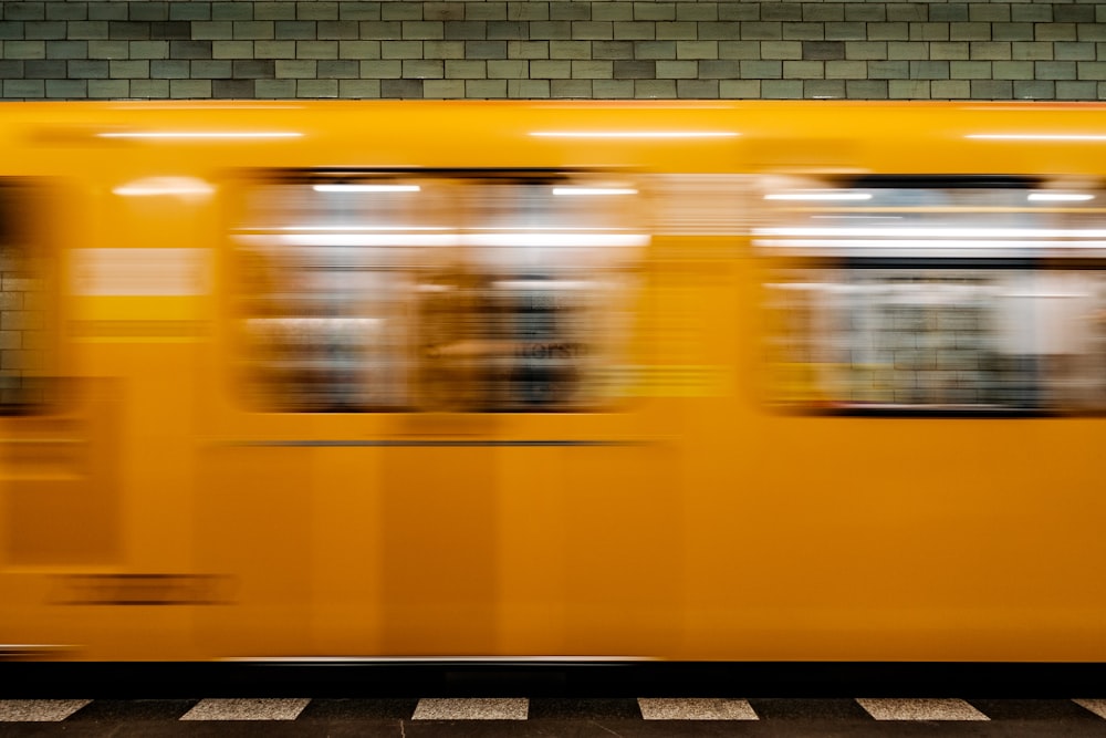 Ein gelber Zug, der an einem Bahnhof vorbeifährt