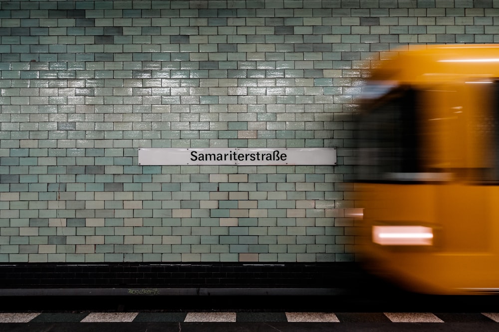 a subway train passing by a subway station sign