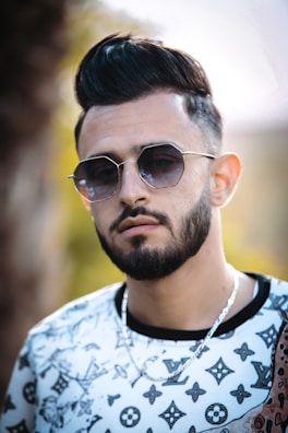 A stylish man wearing a distinctive pendant at an outdoor event.