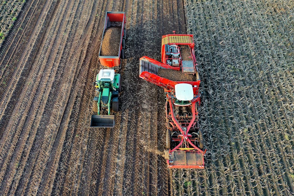 two farming vehicles harvesting on field