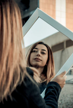 woman holding white framed mirror