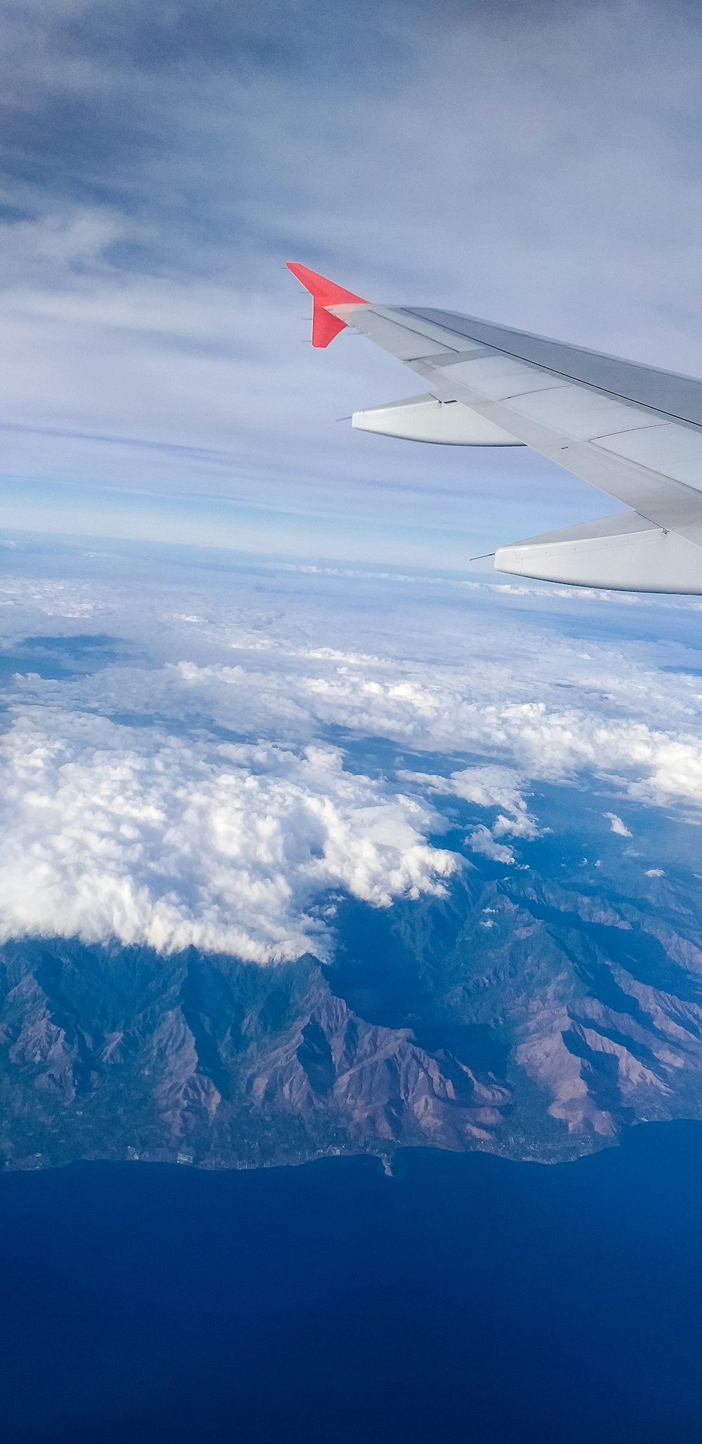 山と雲の上空を飛ぶ飛行機