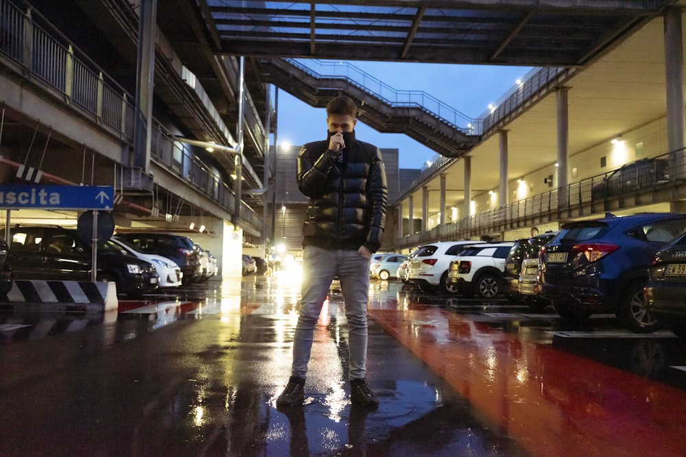 man standing at the parking lot near parked cars