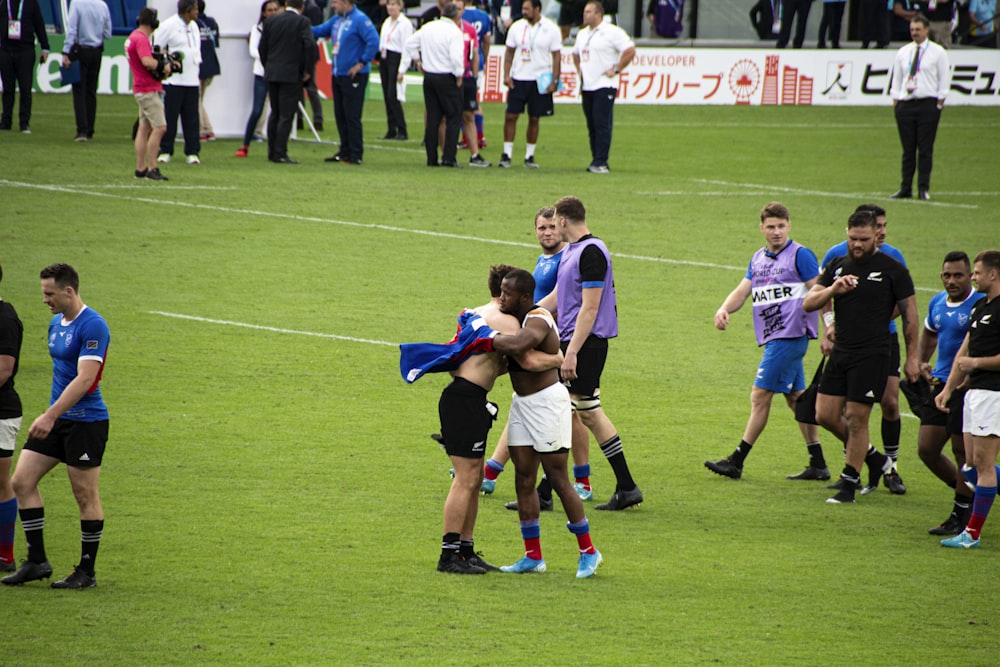 soccer players and people walking, hugging, and standing at the field