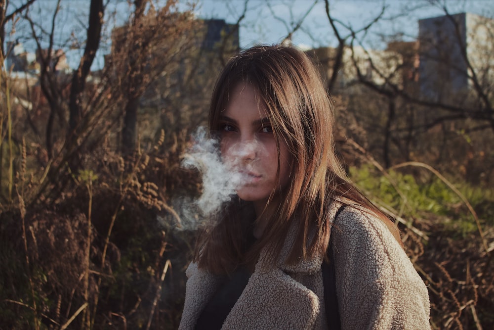 woman doing smoke near trees