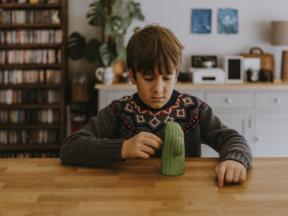 garçon jouant avec une figurine de cactus vert