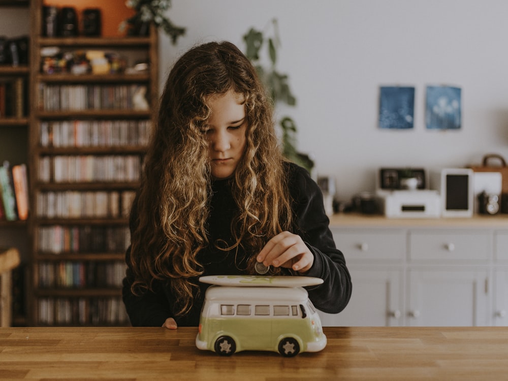 Mädchen trägt schwarzes Sweatshirt und spielt Spielzeugauto