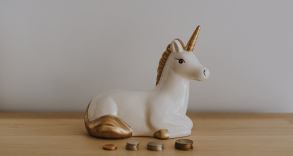 white and gold ceramic unicorn figurine near coins