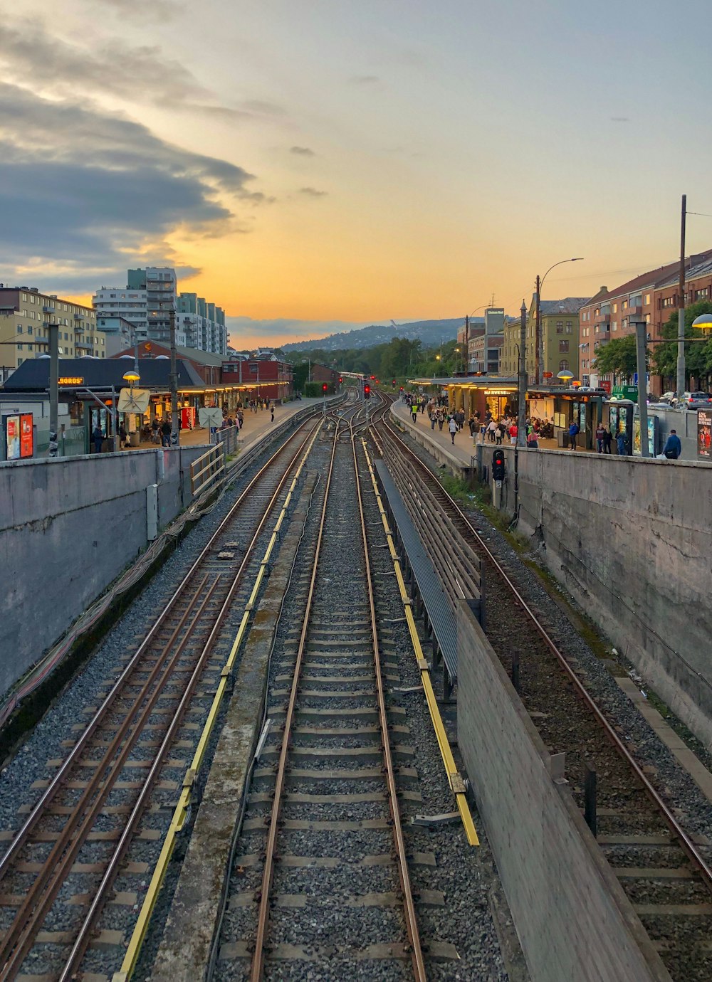 people walking on pathway near train station under white and yellow sky