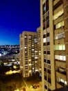 Evening cityscape from the apartment window, lights twinkling below.