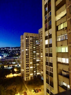 Evening view of a high-rise apartment building with city lights.
