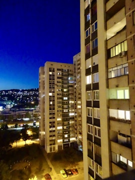 Evening view of the apartment building illuminated against the city skyline.