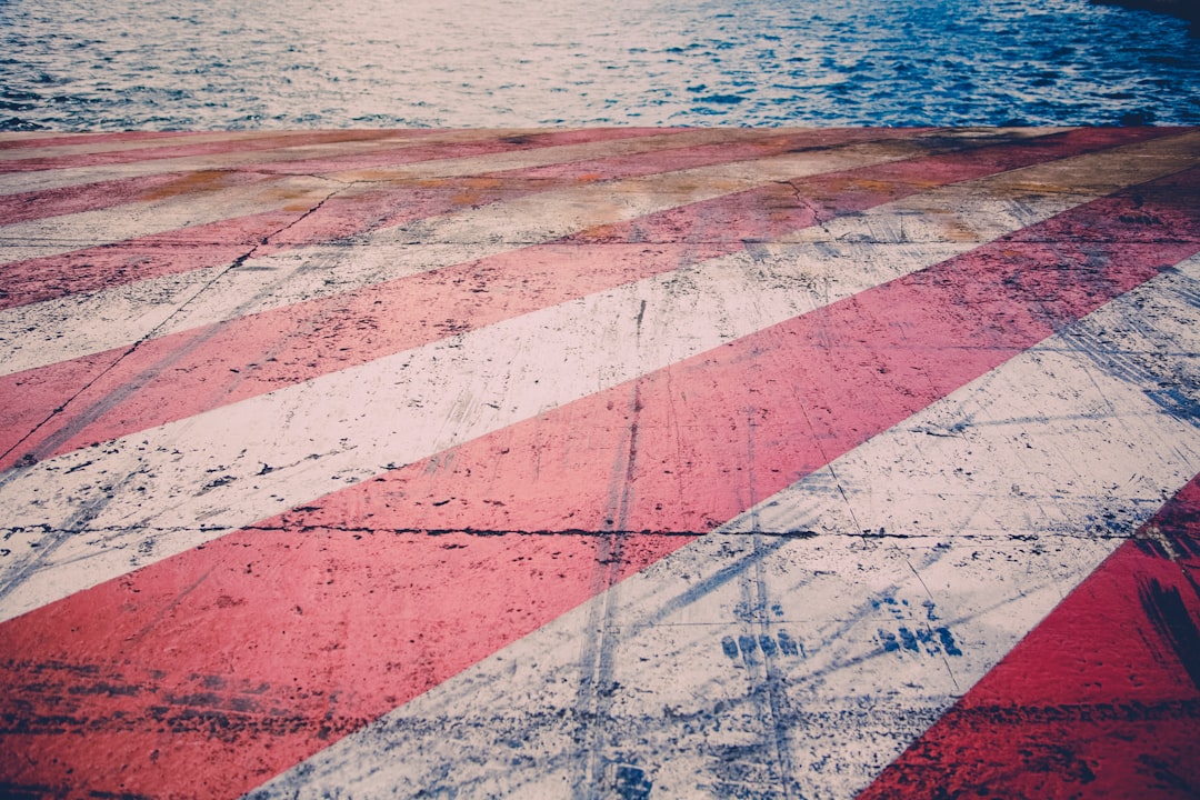 red and white striped painted concrete by body of water