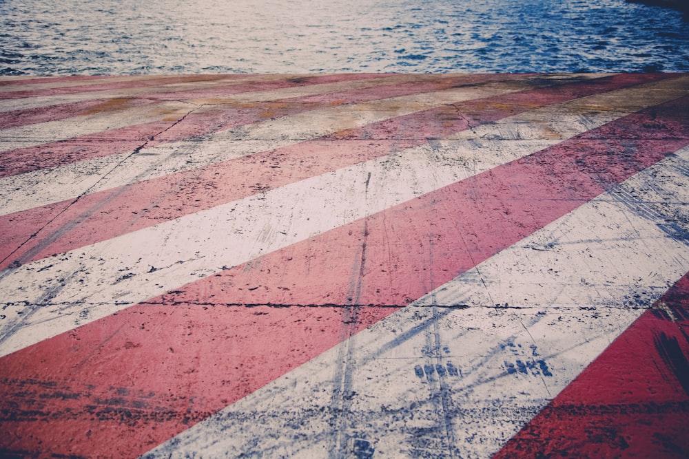 red and white striped painted concrete by body of water
