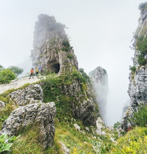 people standing on rocky hill in foggy day