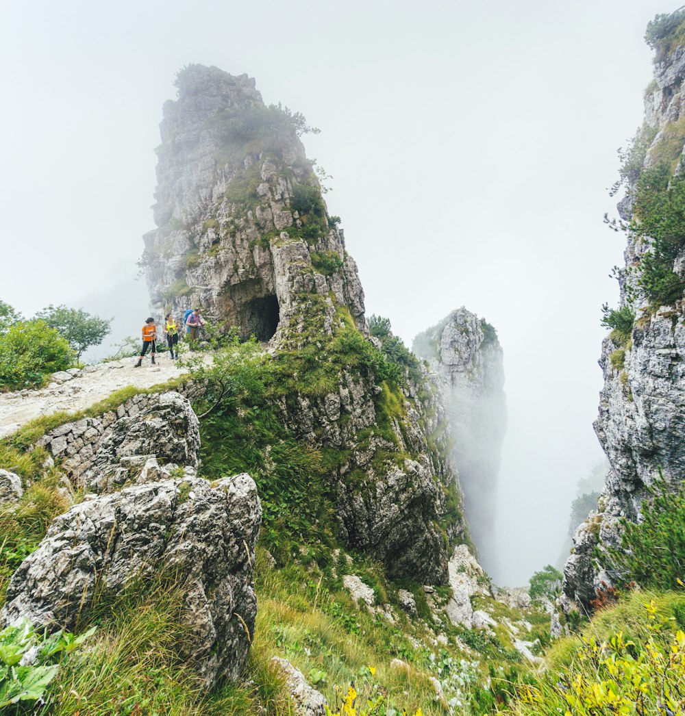 people standing on rocky hill in foggy day