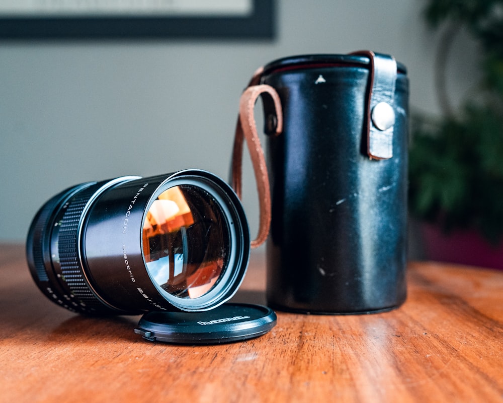 lente de câmera preta com estojo de couro na superfície de madeira