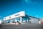 A car dealership building with clear signage for Volvo, Jaguar, and Land Rover brands. The structure features large glass windows and a metallic exterior, situated on a slightly elevated area with a clear, blue sky in the background.