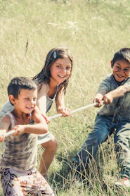 three kids pulling on a rope during daytime