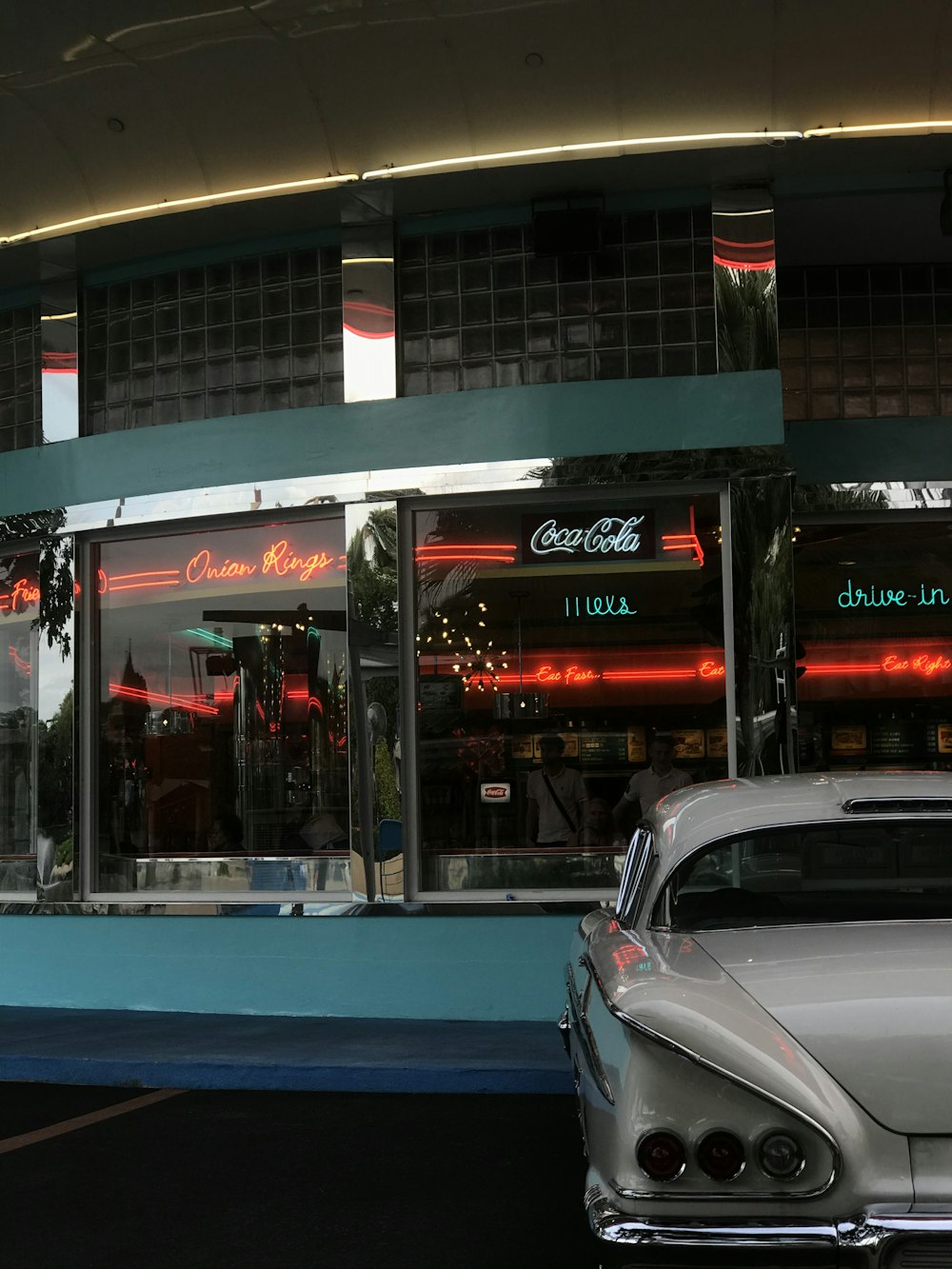 white vehicle parked by building with glass windows