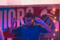 A player celebrating with raised hands in front of a glowing game screen.