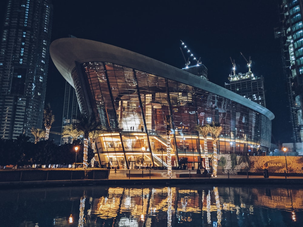 gray curtain wall building reflecting on body of water at night