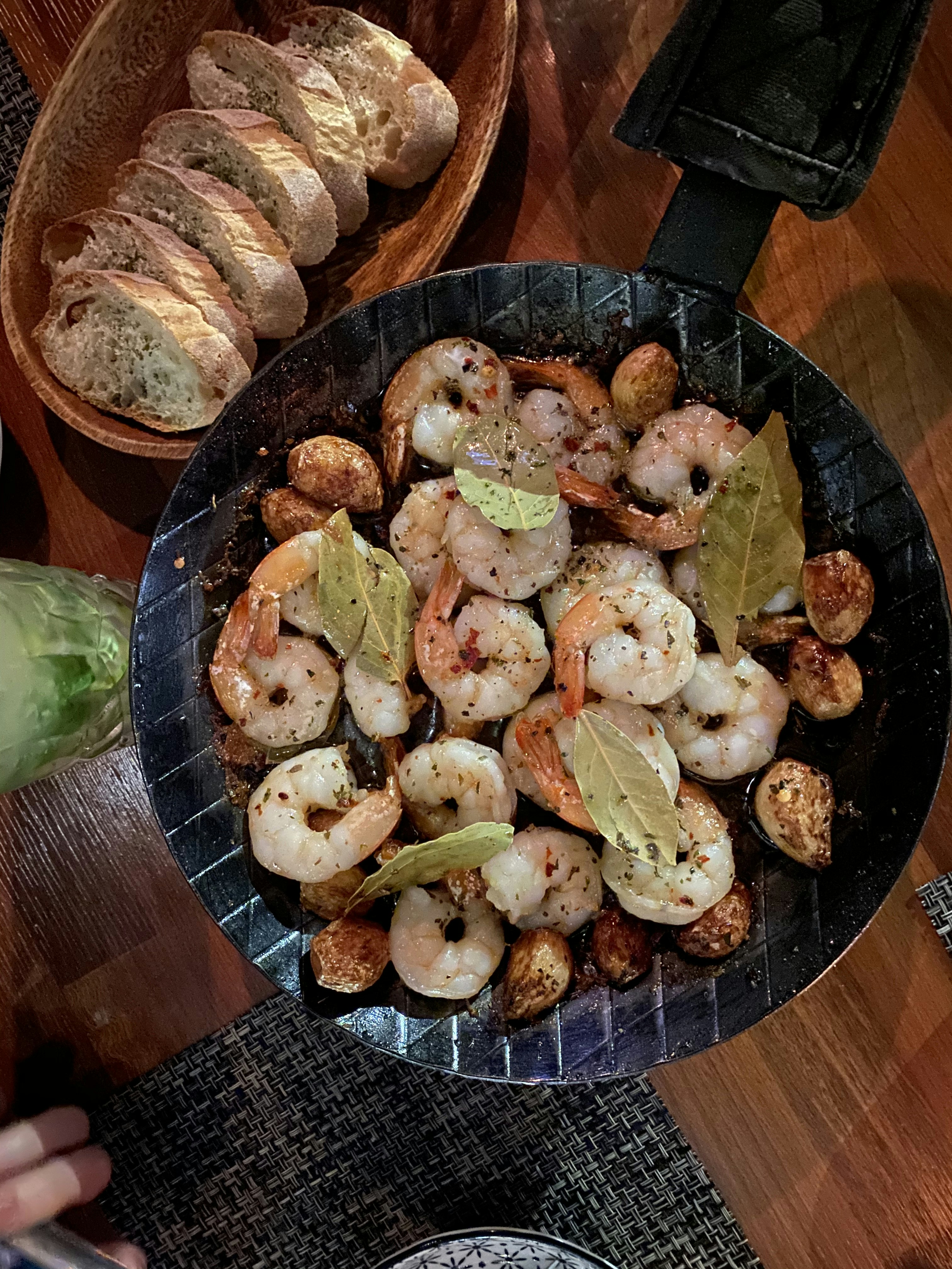 A skillet of garlic shrimp served with rustic bread.