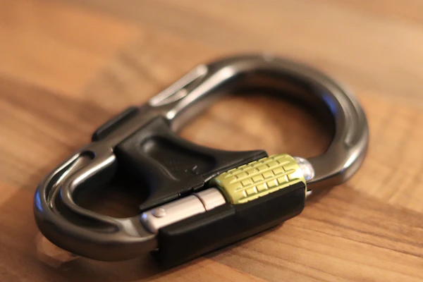 Grid display of carabiners including Black Diamond RockLock Magnetron and Petzl OK Screw-Lock on a textured slate grey background.