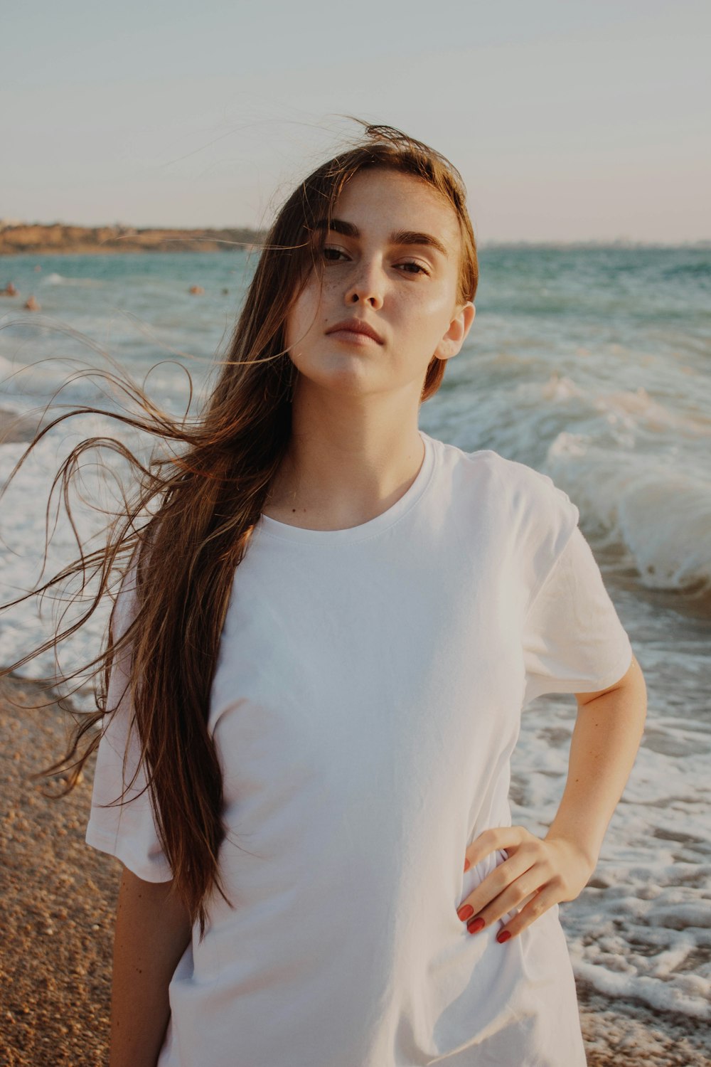 woman in white shirt standing on seashore during daytime