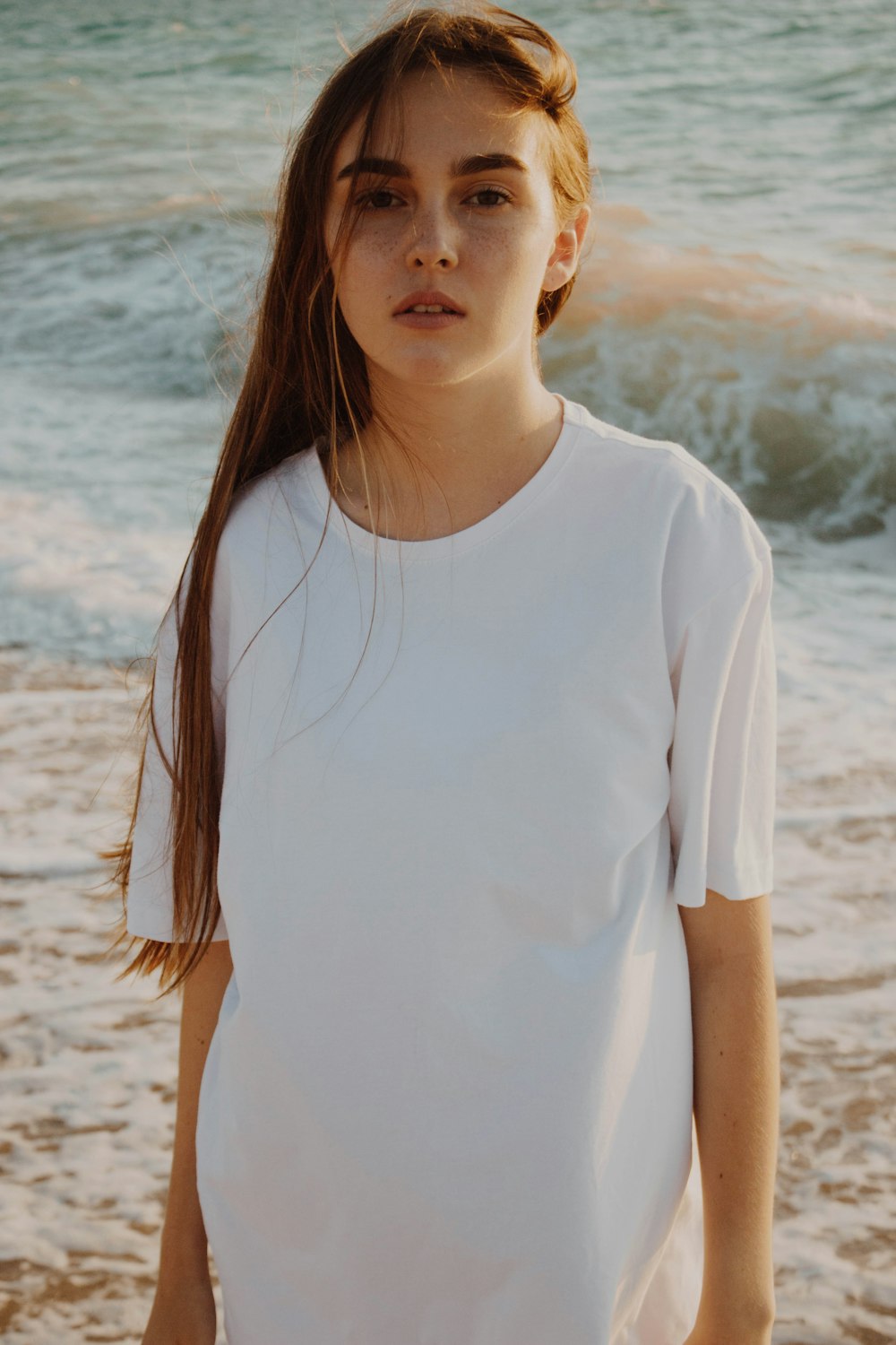 woman in white crew-neck shirt standing on seashore during daytime