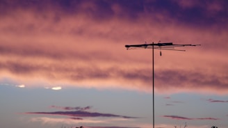 A technician installing an internet antenna on a rooftop at sunset