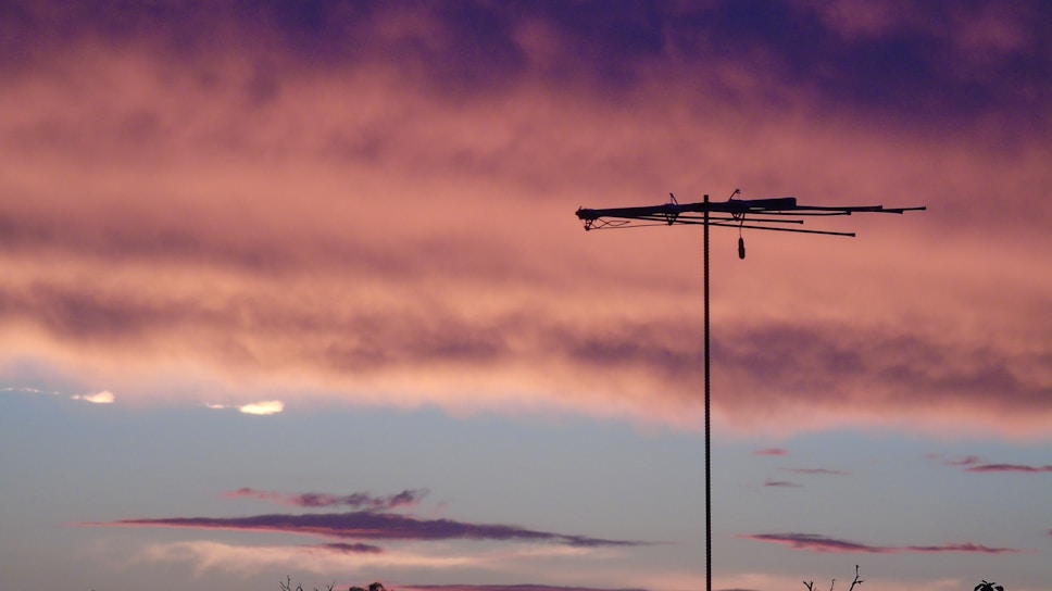 Keith Murray setting up his ham radio antenna against a sunset sky.