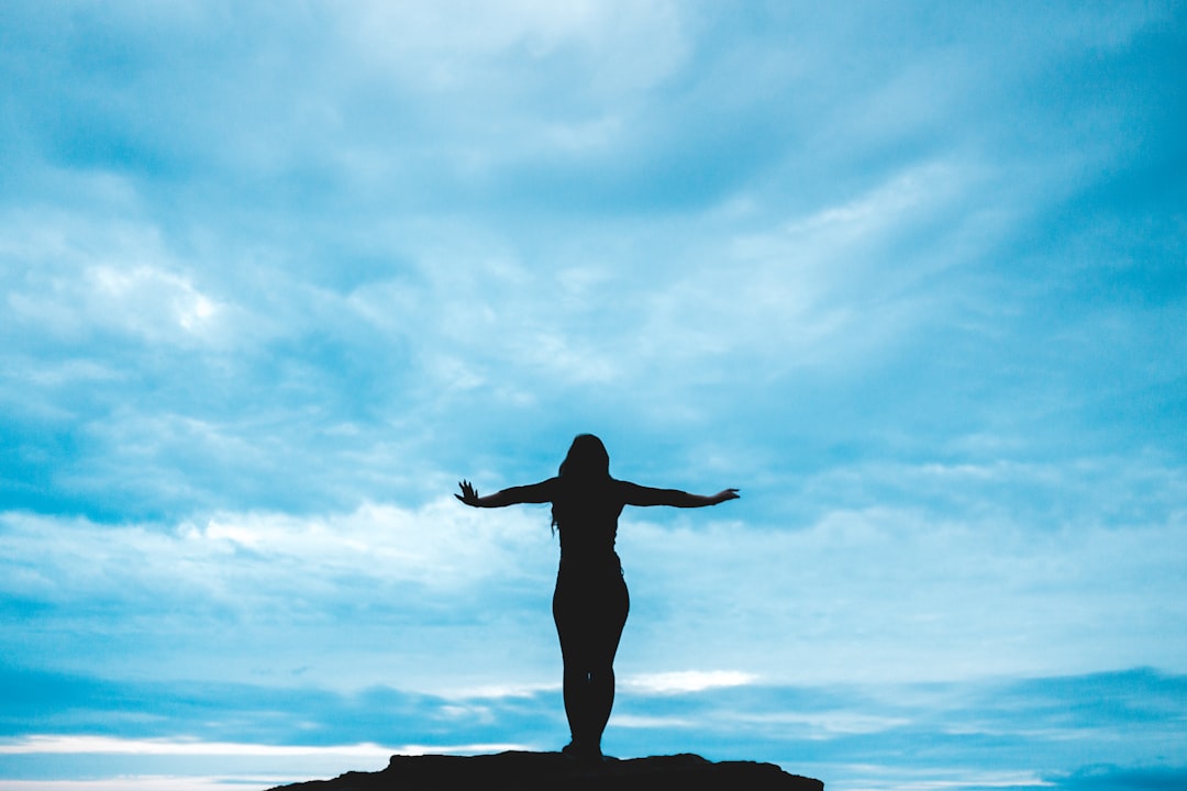 silhouette photography of woman raising her hands