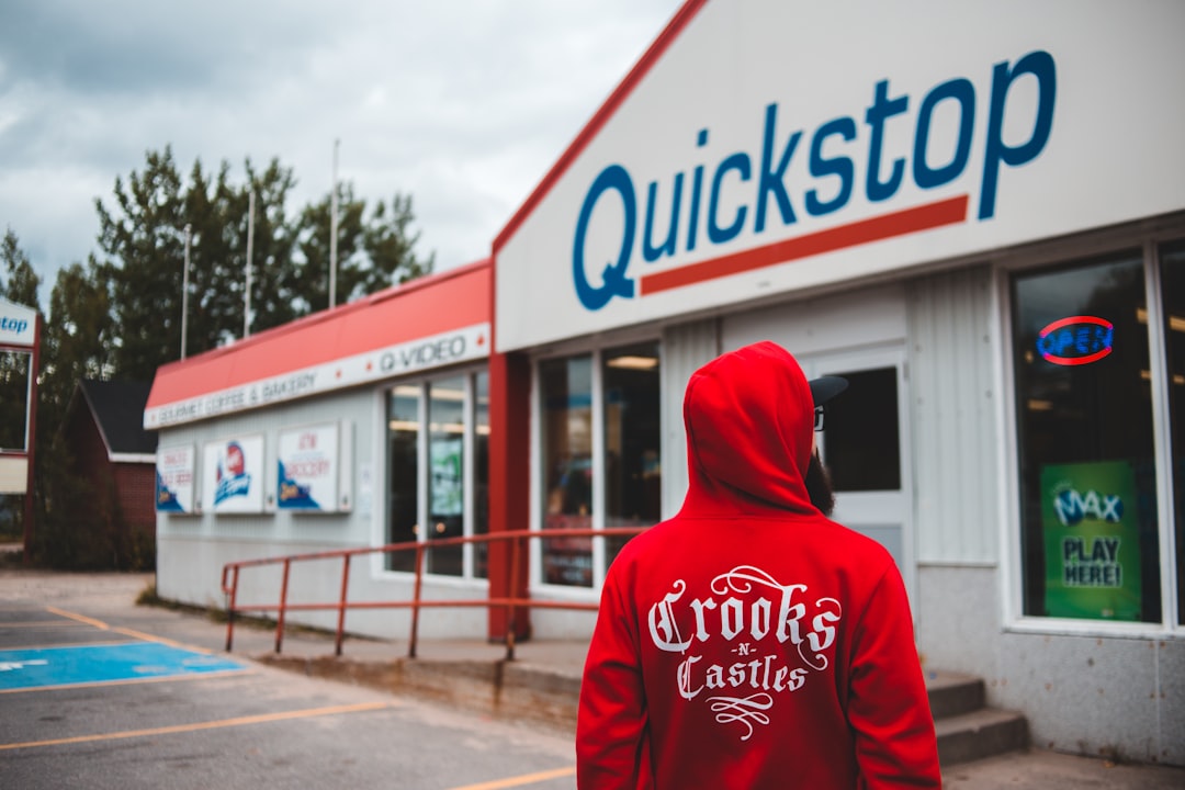 man in red Crooks hoodie standing front of store