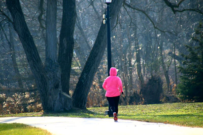 A model wearing a pastel-toned hoodie jogging in a city park with natural light.