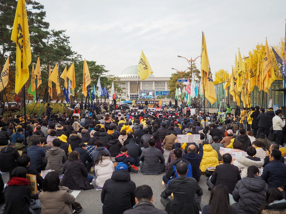 people sitting on ground with yellow flags