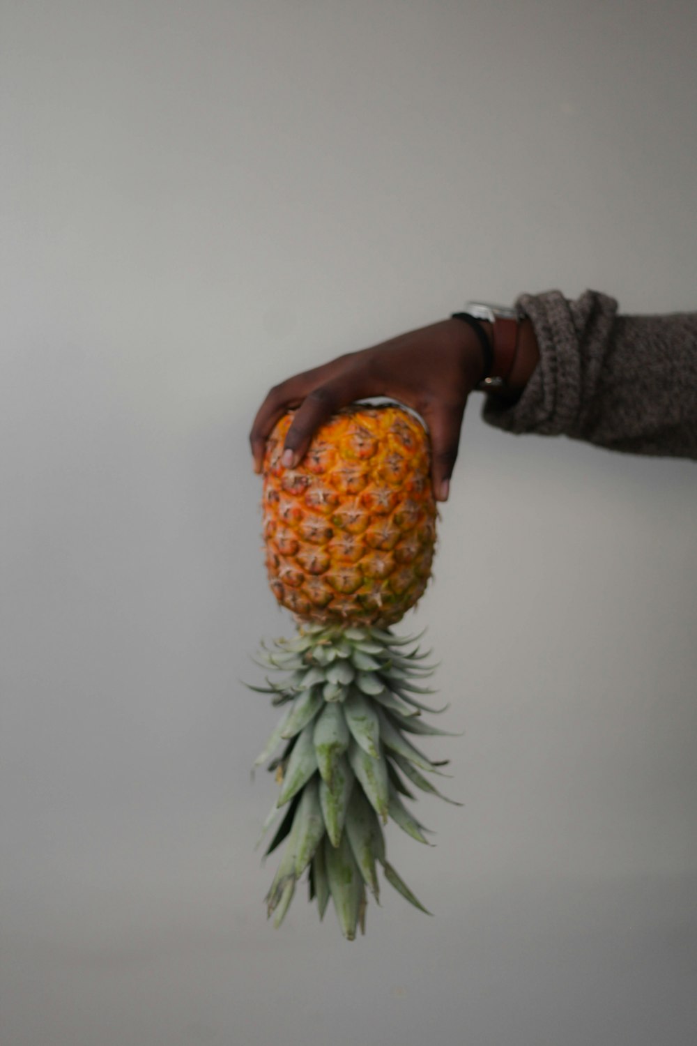 person holding pineapple downwards