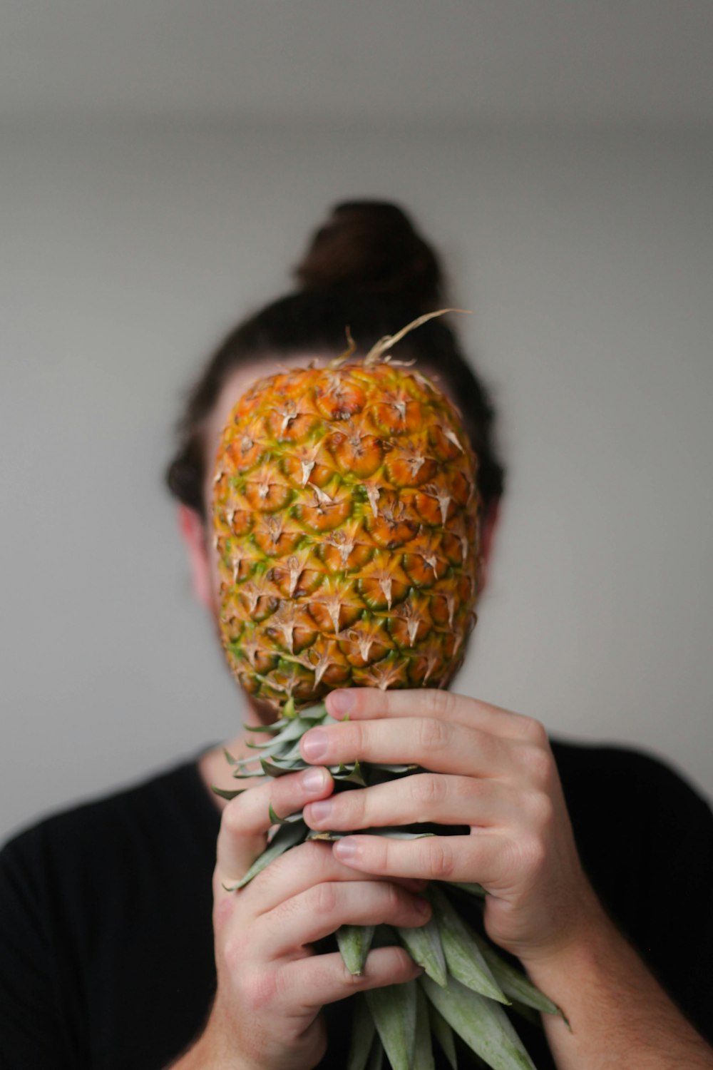 person in black shirt holding pineapple