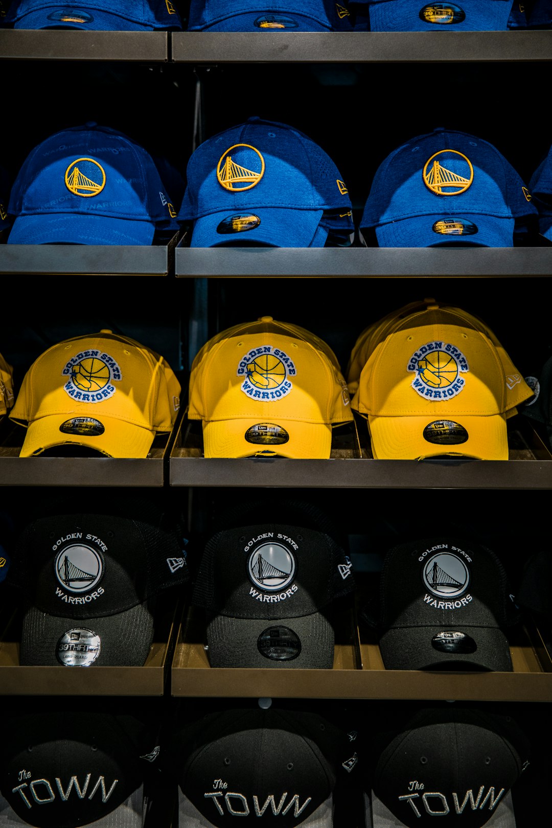 three assorted-color Golden State Warriors caps on shelf
