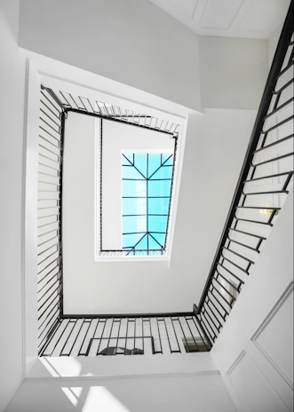 Interior view of a high-end residential stairwell with a large skylight flooding natural light.
