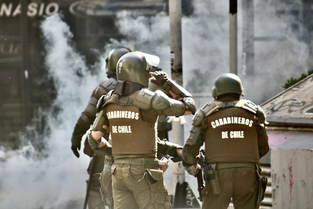 three men in riot armor near buildings