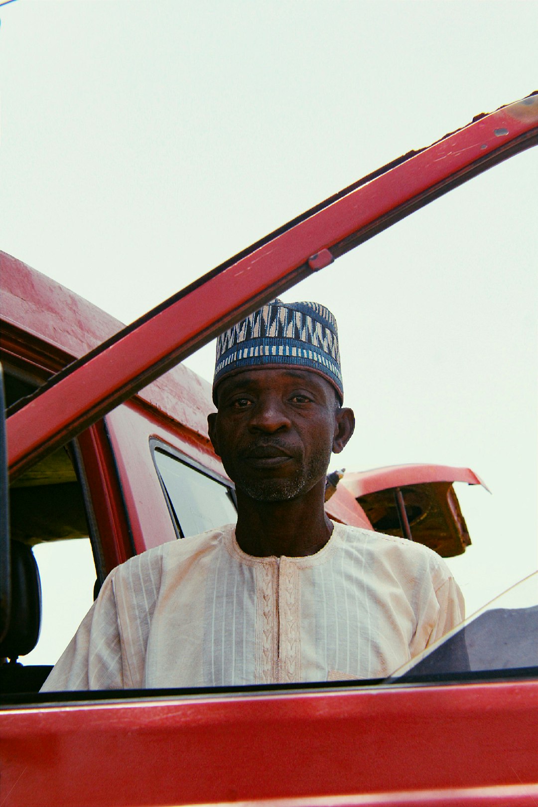 man standing on open door of red van