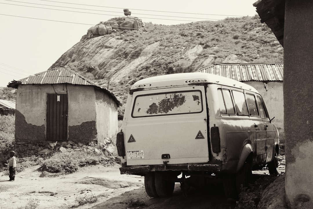 grayscale photography of vehicle parked beside house